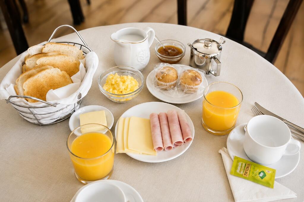 Continental breakfast spread at Hotel Rondo with toasted breads, scrambled eggs, ham, cheese, fresh orange juice and Twinings tea